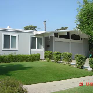 A mid-century modern house with a well-maintained lawn and garden.