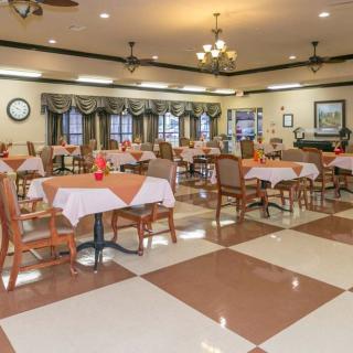 An elegantly decorated dining area featuring multiple tables and chairs, illuminated by chandeliers.