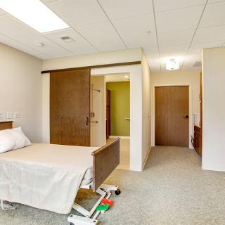 A hospital room with a bed and sliding door inside a medical facility.