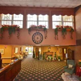 A cozy hotel lobby featuring vintage decor with ornamental plants and a large clock.