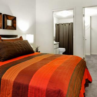A modern bedroom with a colorful striped blanket and attached bathroom.