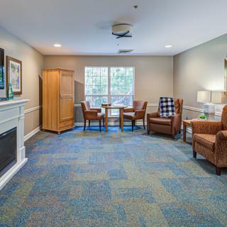 A cozy living room with comfortable seating, a fireplace, and a table by the window.