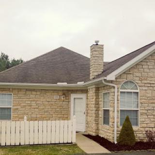A quaint stone house featuring a chimney and surrounded by a white picket fence.