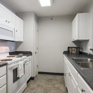 A modern kitchen featuring white cabinetry and essential appliances.
