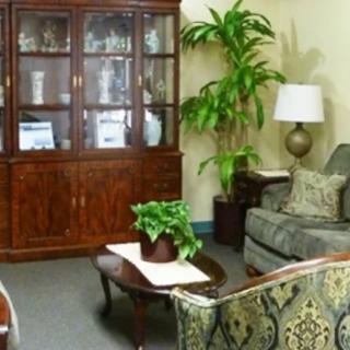 A cozy living room featuring a sofa, coffee table, wooden cabinet, and indoor plants.