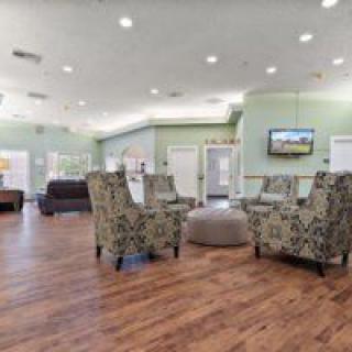 A spacious lobby with patterned chairs, a television, and wood flooring.