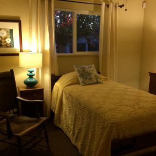 A cozy bedroom with a single bed and glowing lamp.