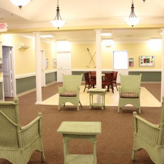 A well-lit lobby area with wicker chairs and tables arranged for seating.