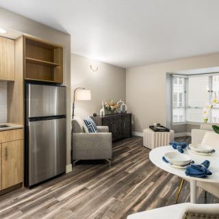 A modern open-plan living room and kitchen area with wood flooring and contemporary furnishings.