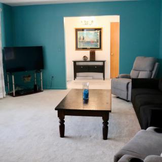 A cozy living room with a sofa, coffee table, and television against a teal accent wall.
