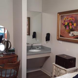 A cozy bathroom space featuring a vanity, artwork, and stylish furniture.