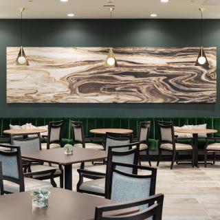 A modern restaurant interior featuring a large abstract artwork and pendant lighting.