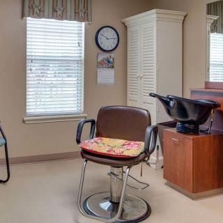 An empty salon with a barber chair and hair washing station.