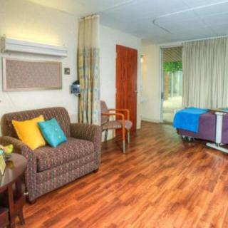 A hospital room featuring a sofa, bed, and wooden flooring.