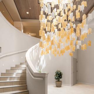 A modern interior with a curved staircase and a striking art installation hanging from the ceiling.