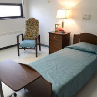 A simple hospital room with a single bed and basic furnishings.