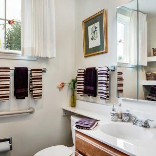 A well-organized bathroom with a sink, mirror, and neatly arranged towels.