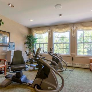 A fitness room with cardio machines and large windows allowing natural light.