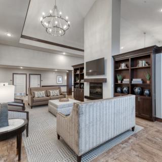 A modern living room with elegant decor, featuring a chandelier, fireplace, and bookshelves.