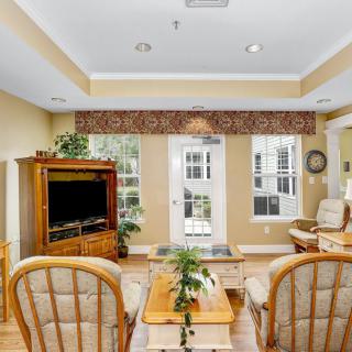 A cozy living room with wooden furniture, a TV, and large windows that let in natural light.