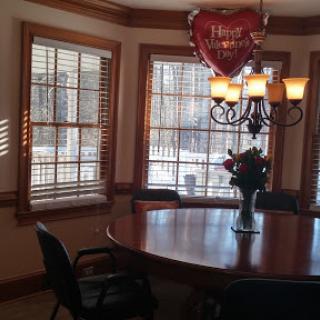 A cozy dining room featuring a wooden table, elegant chandelier, and decorative heart balloon.
