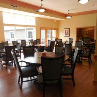 A well-lit dining area with multiple round tables and chairs.