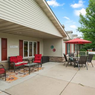 A cozy patio with red-cushioned seating and an umbrella-covered table, perfect for enjoying a sunny day.