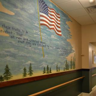 A hallway featuring a mural with the American flag and scenic background.