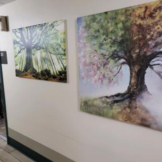 Two paintings of trees displayed in a hallway.