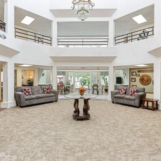 A spacious and elegantly decorated lobby featuring sofas, a central table, and a chandelier.