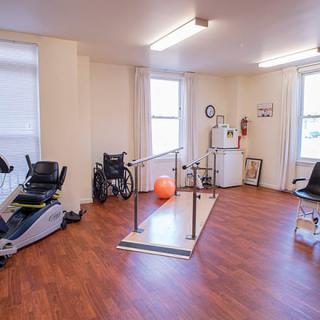 A physical therapy room equipped with exercise machines and parallel bars for rehabilitation purposes.
