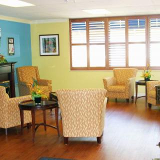A cozy living room with comfortable chairs, tables, and indoor plants.
