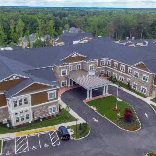 Aerial view of a large building with a parking lot and surrounding greenery.
