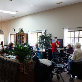 A group of elderly people in a nursing home setting, engaged in a social activity.