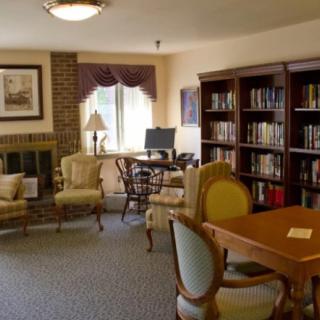 A cozy library room with bookshelves, seating area, and a computer desk.