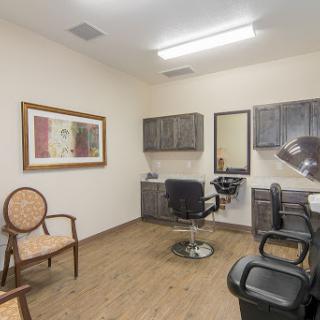 A well-lit hair salon featuring a barber chair, waiting area, and decorative artwork.