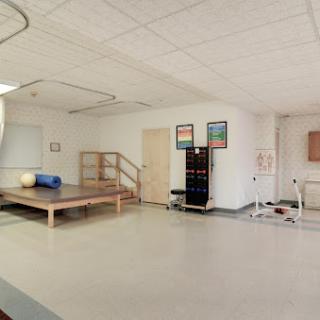 A spacious therapy room designed for rehabilitation exercises, featuring various equipment and a wooden platform.