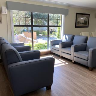 A cozy living room with blue and white sofas arranged around a large window providing ample natural light.