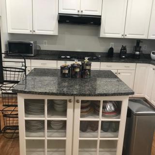 A modern kitchen with a central island, surrounded by white cabinets and various appliances.