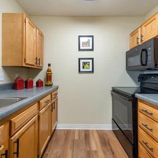 A modern kitchen with wooden cabinets and black appliances.