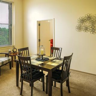 A cozy dining area featuring a wooden table and chairs, complemented by simple decor and natural light from the window.