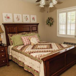 A cozy bedroom with a wooden bed, patterned quilt, and decorative wall art.