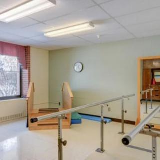 A rehabilitation room equipped with parallel bars and stairs for physical therapy exercises.