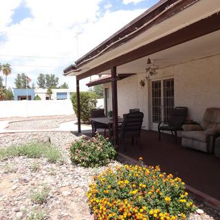 A sunny patio with outdoor seating and vibrant flowers in a desert landscape.