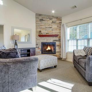 Cozy living room with a fireplace, featuring comfortable seating and ample natural light from the window.