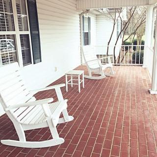 A cozy porch with white rocking chairs on a brick floor.