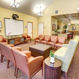 A spacious and well-lit waiting room featuring comfortable seating and a television.