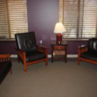 A cozy living room setup with two chairs, a small table, and a lamp against a purple wall.