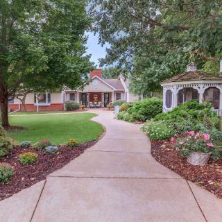 A scenic pathway leading to a house, surrounded by lush gardens and a charming gazebo.