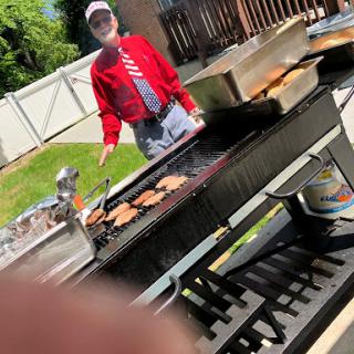 A man grilling burgers on a sunny day.